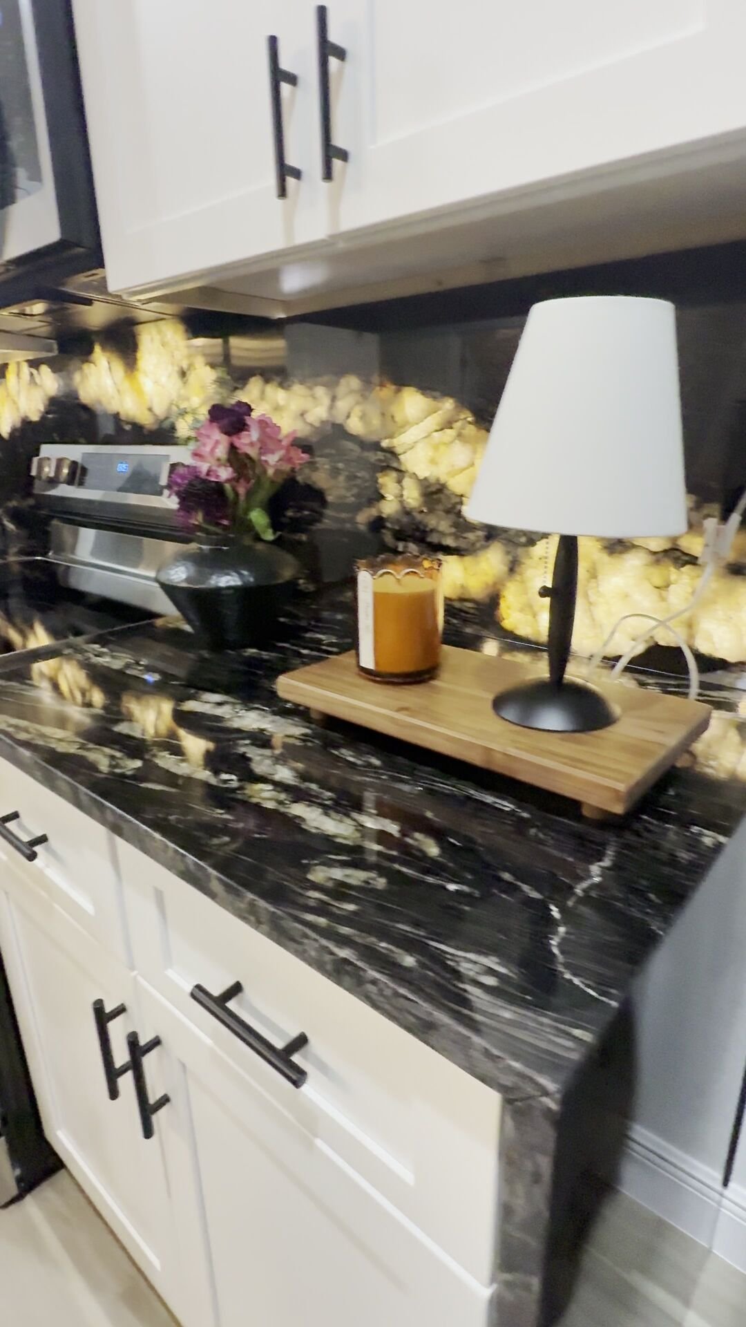 Custom black and gold natural stone waterfall island, backlit at night, by Stone Experience